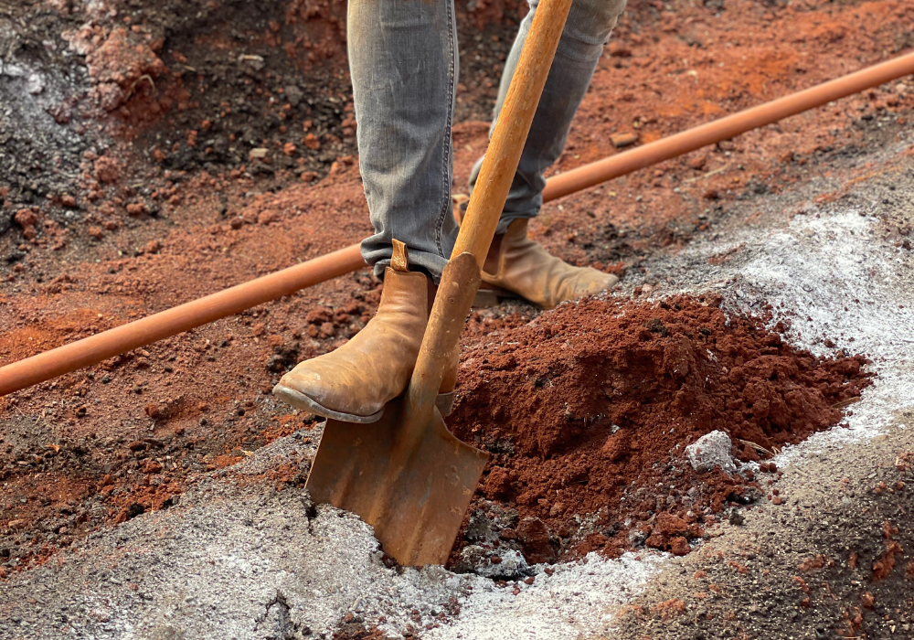 Man shoveling red soil