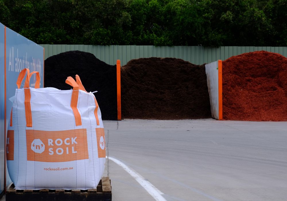 Bulk bag sitting next to bins full of red, black and brown mulch