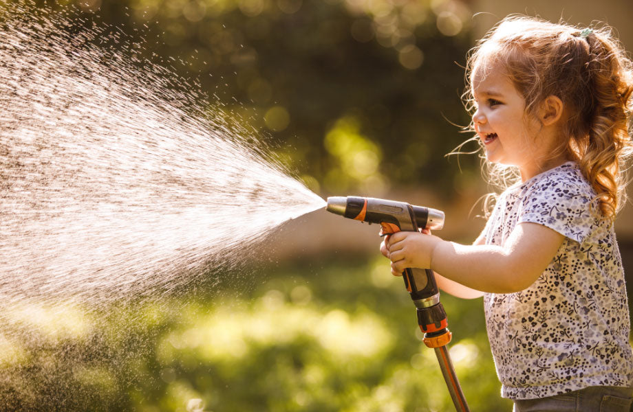 Little Girl Watering Garden for How Often Should You Water Your Lawn