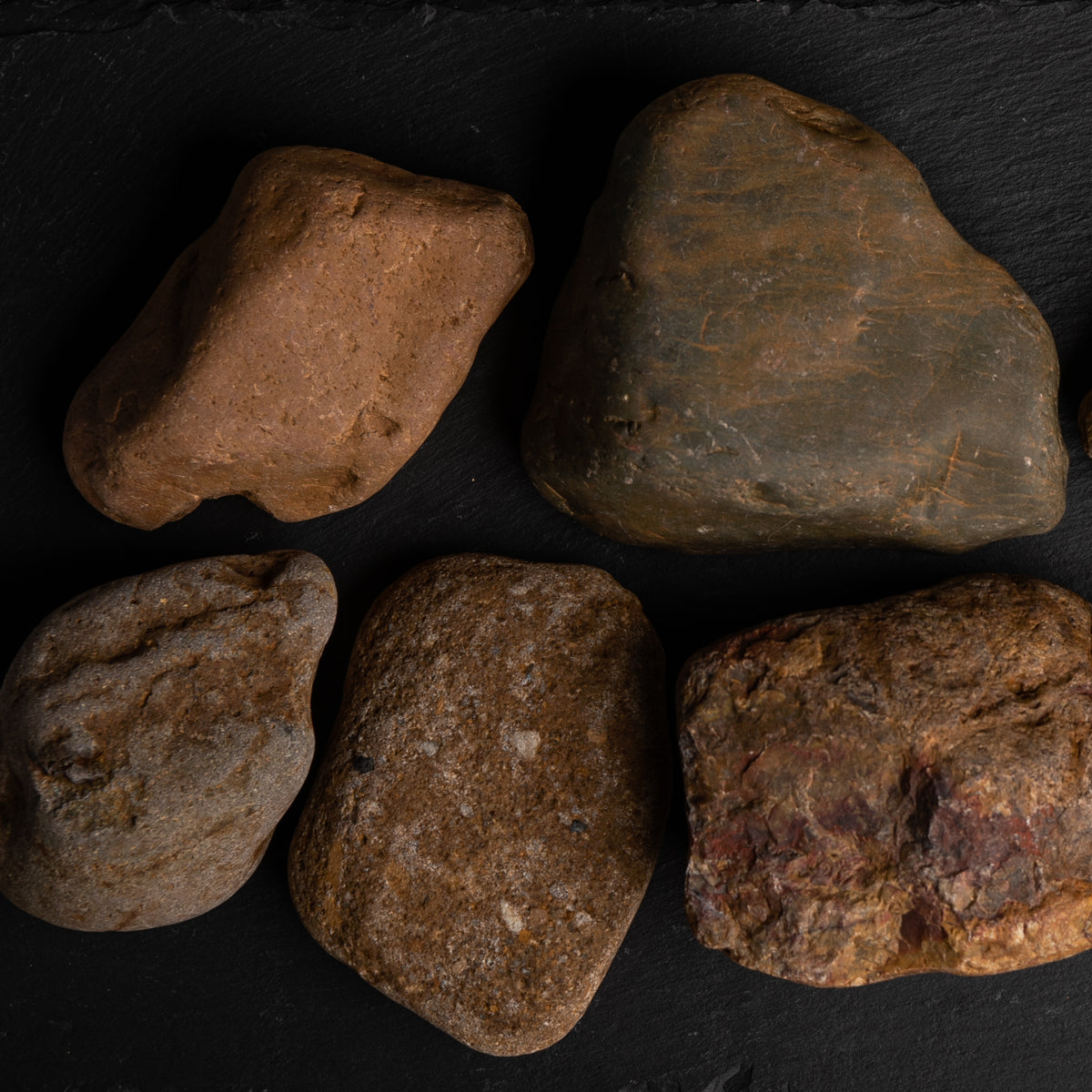 Five brown stones on a black slate surface