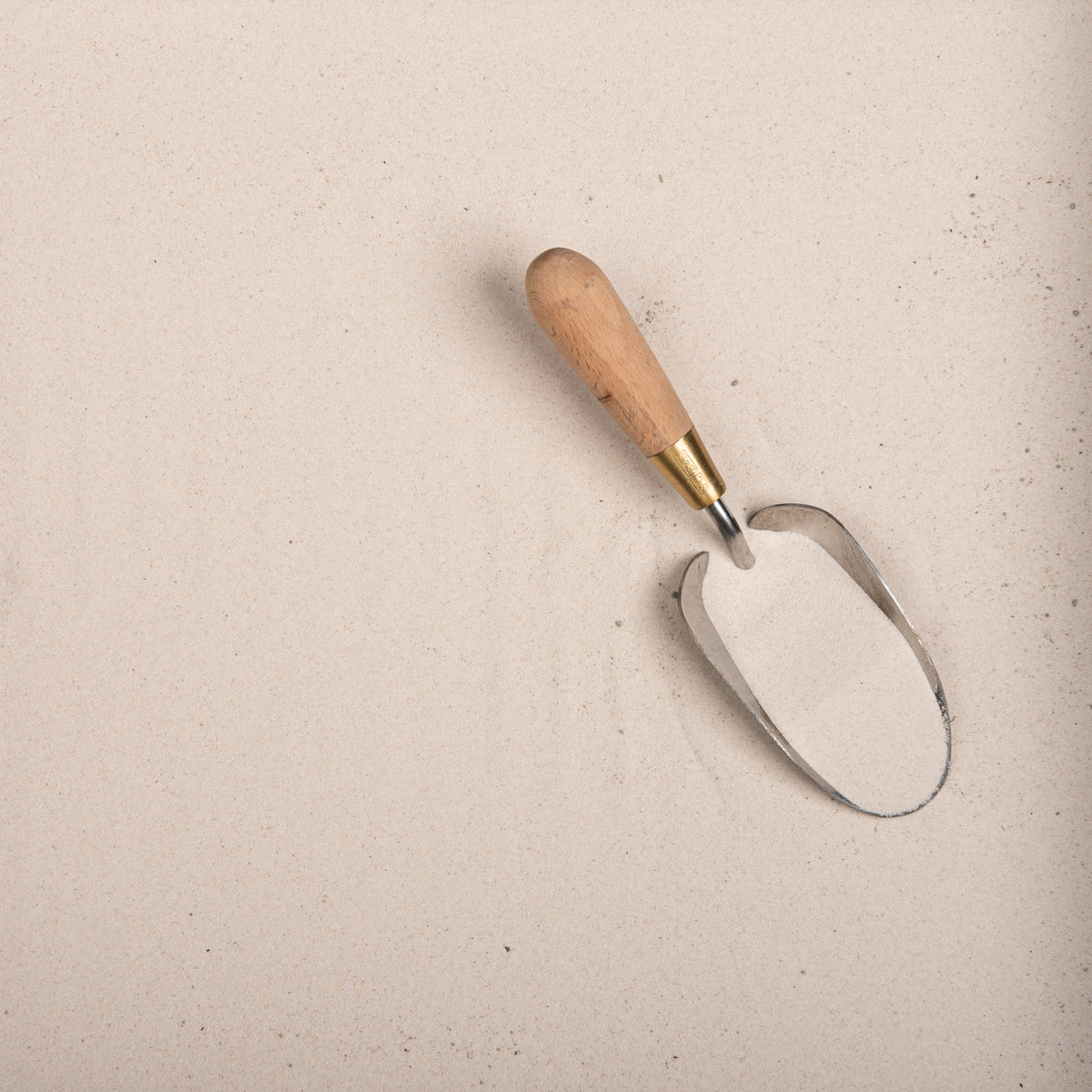 Metal garden trowel with wooden handle on a sand