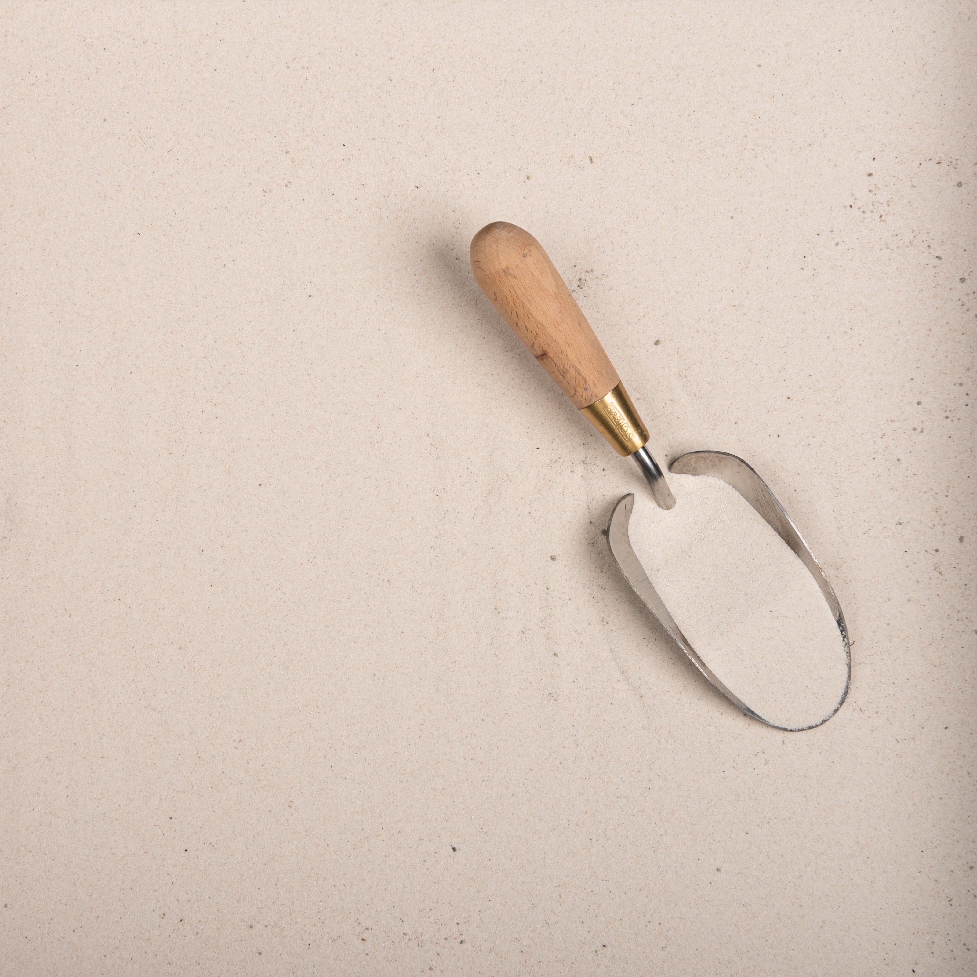 Metal garden trowel with wooden handle on a sand