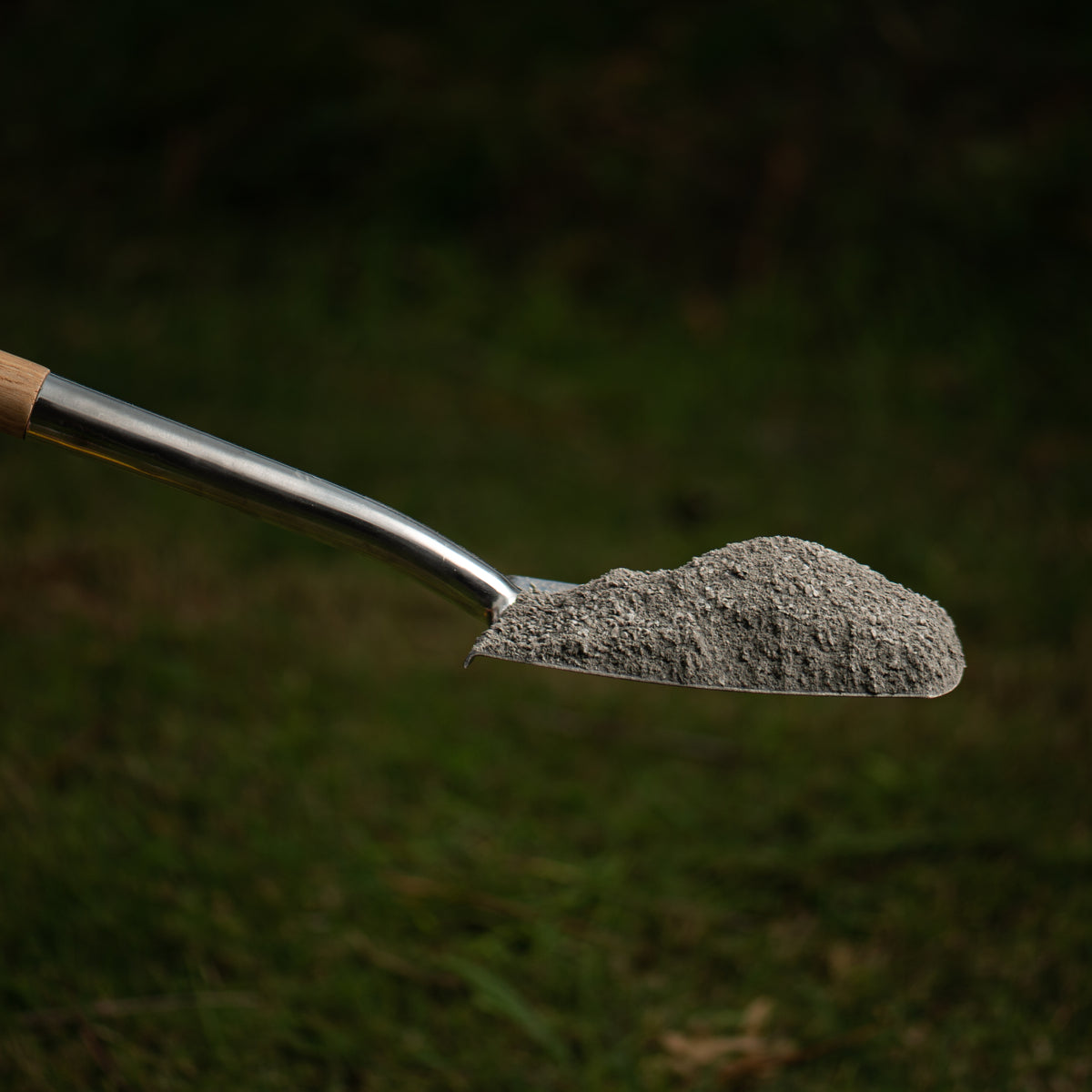 metal shovel holding crusher dust on grassy background
