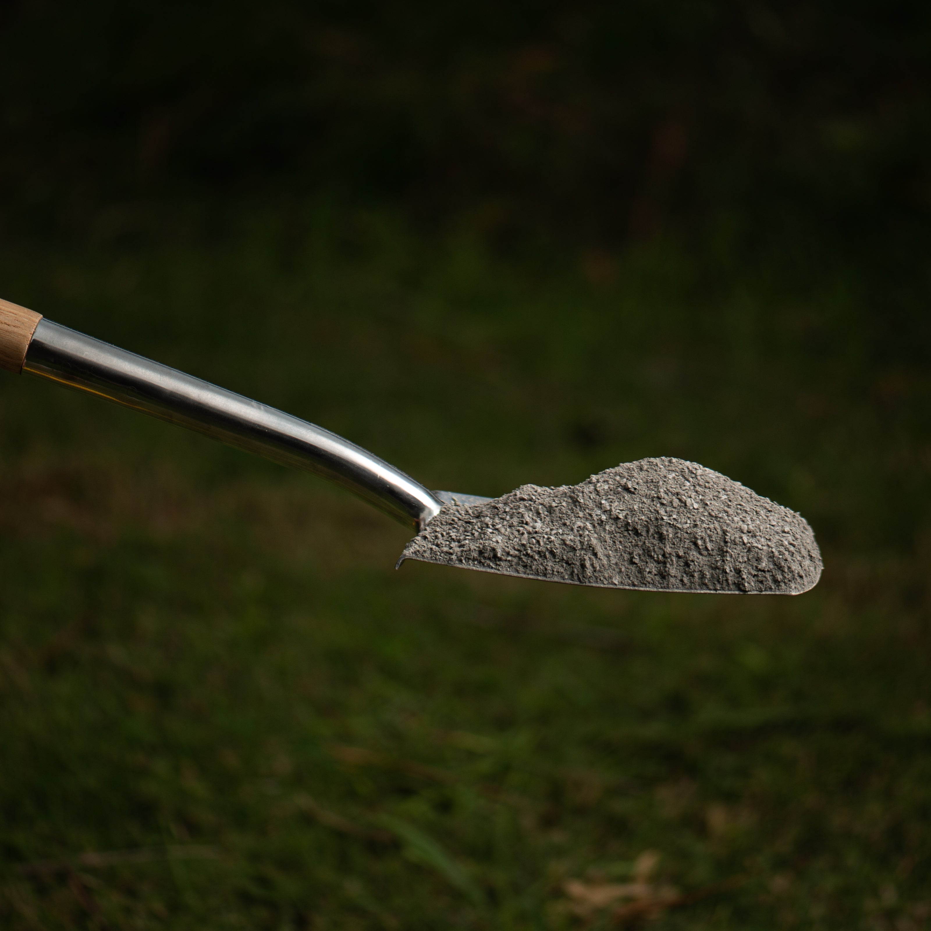 metal shovel holding crusher dust on grassy background