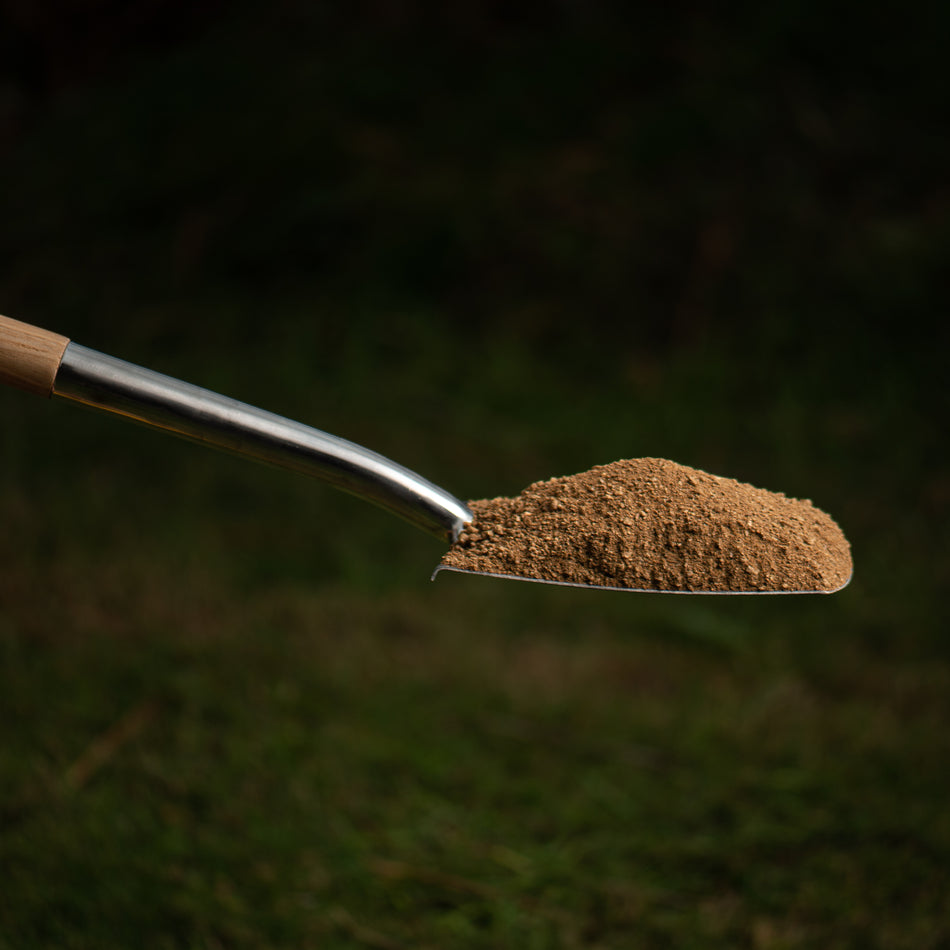 metal shovel with sand on grassy background
