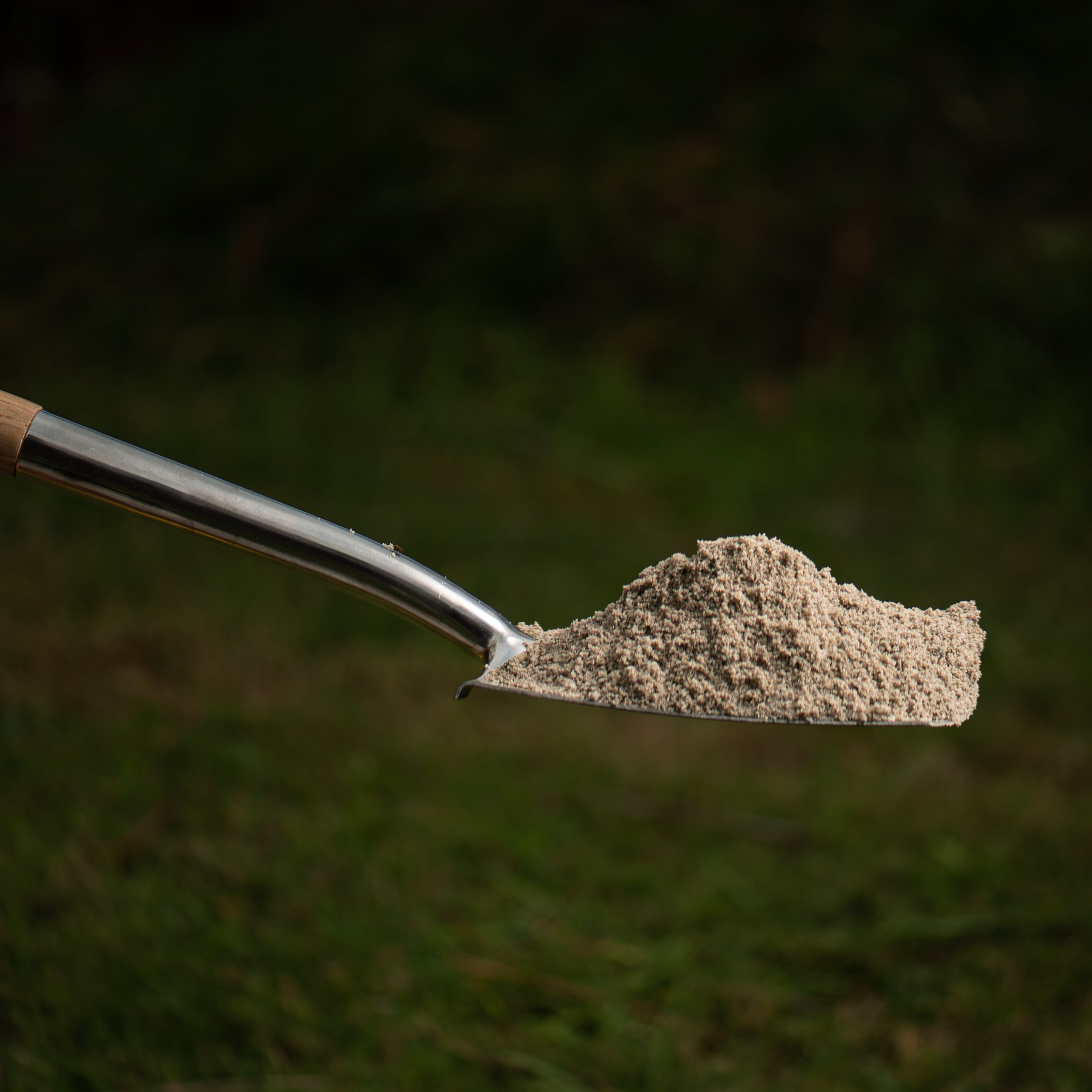 metal shovel with sand on a grassy background