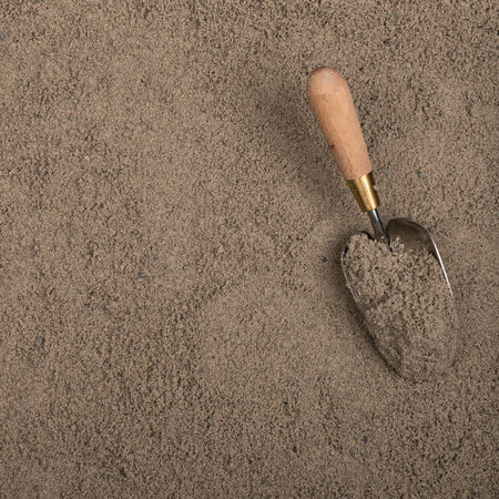 Trowel with wooden handle and metal blade in sand
