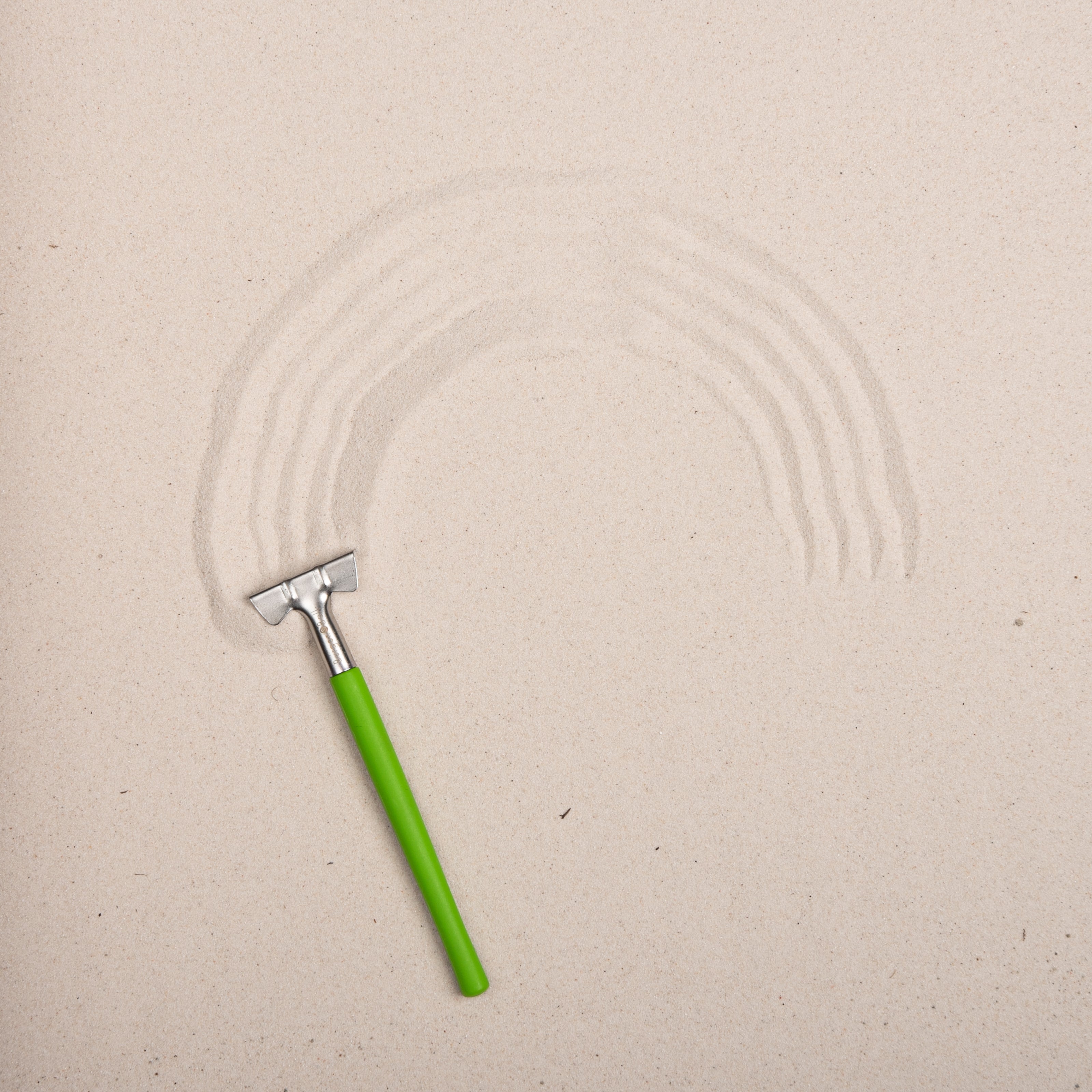 Green sanding block with sanding patterns on a beige surface