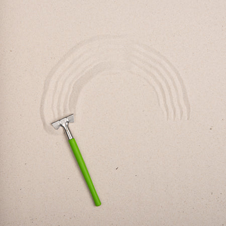 Green sanding block with sanding patterns on a beige surface