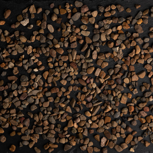 Close-up of small pebbles in various shades of brown and orange on a dark background