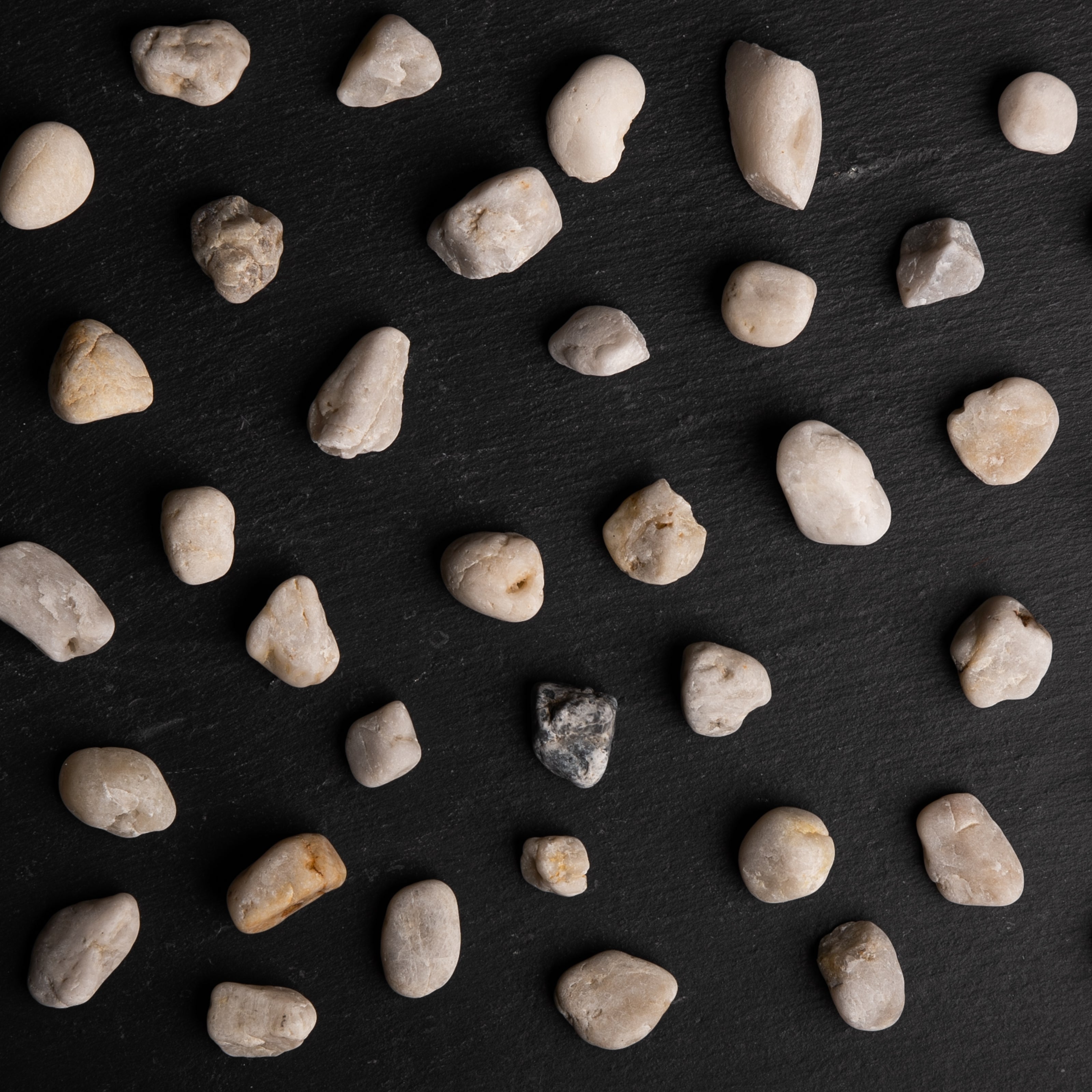 Small rocks scattered on a dark slate surface