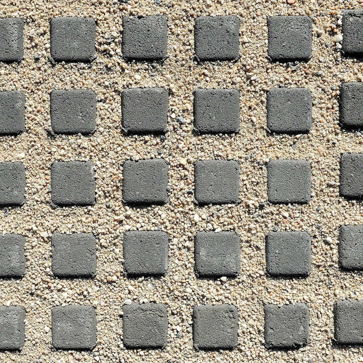 Pattern of gray square stones on a sandy surface