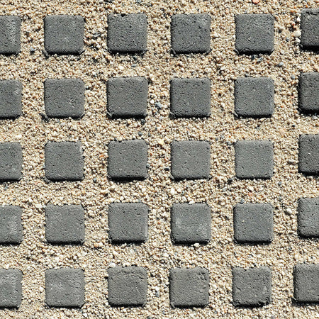 Pattern of gray square stones on a sandy surface