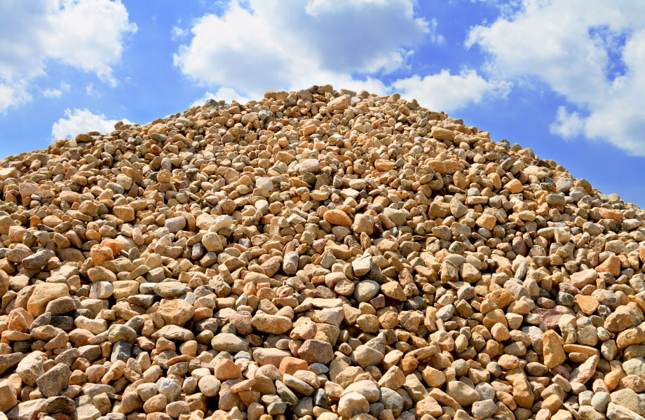 pile of landscaping rocks against a blue sky with clouds deposited by a landscape supplier