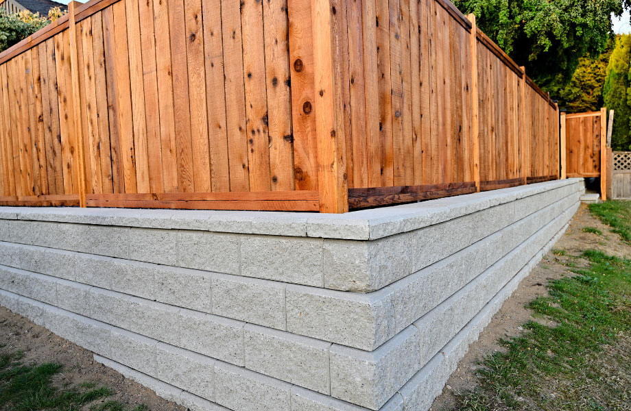 image of clean retaining wall and red wood fence for masonry maintenance 
