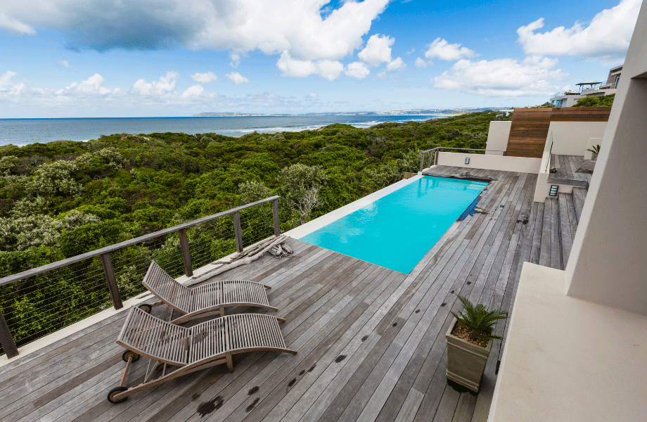 image of grey decking with blue pool overlooking the ocean and the rainforest