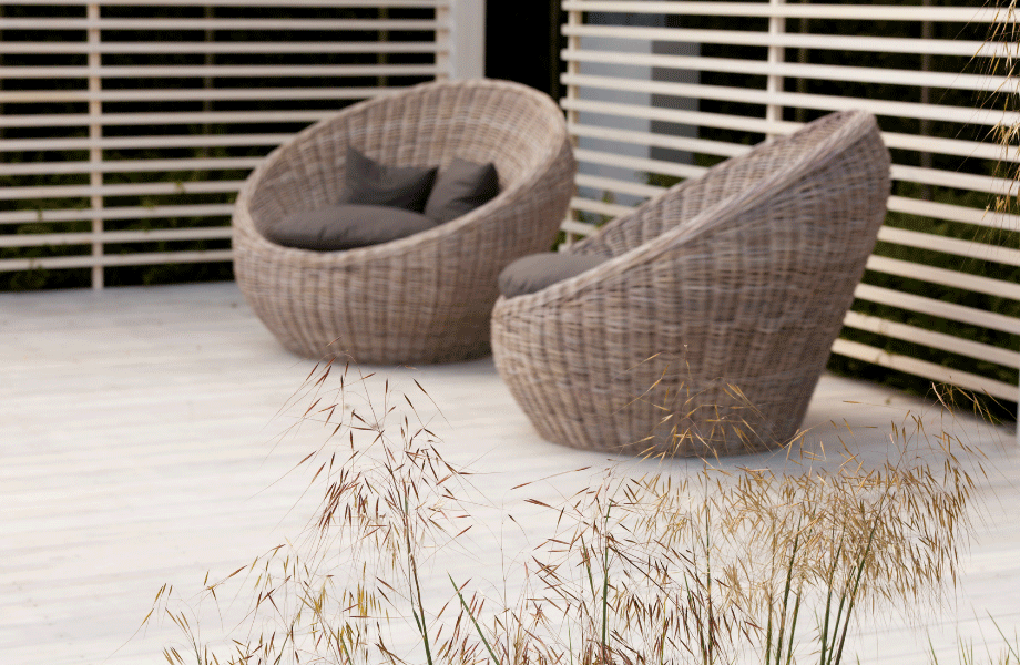 two light brown wicker bucket chairs with a light grey deck and beige lattice behind for a neutral garden colour scheme