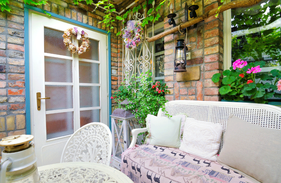 feature corner garden with charming wrought iron table and chair and a little couch, with plantings around the walls and a lamp