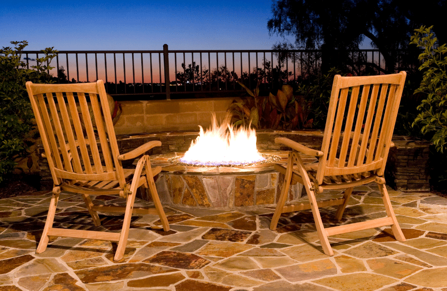 feature corner with a fire pit, wooden chairs and organic paving with a sunset in the background