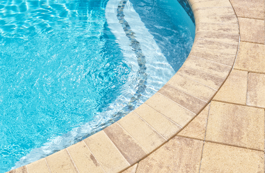 beige pavers in a curved shape outlining a bright blue pool for types of pavers