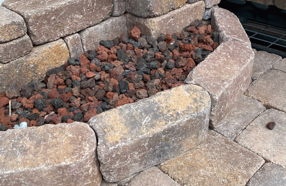 stacked pavers making a small garden bed filled with brown and grey pebbles