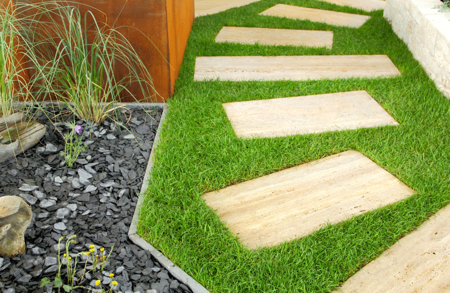 timber steppers along a grassy patch against a wooden wall and grey pebbled garden bed