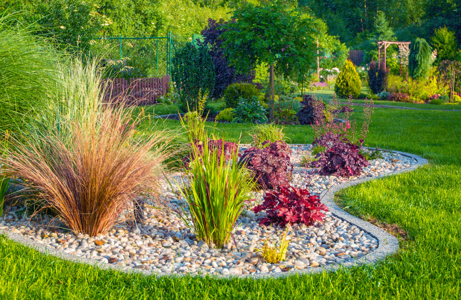 bright garden foliage in a natural shaped garden bed with pebbles and garden pavers edging in the middle of a bright green lawn