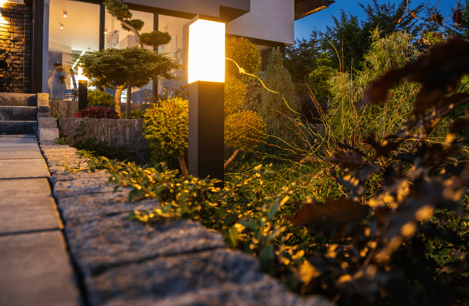 garden-lighting up a paved path in a garden bed with plants at dusk