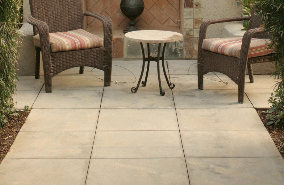 paved-flooring on a patio with two wicker chairs and small marble table in front of a terra cotta water feature